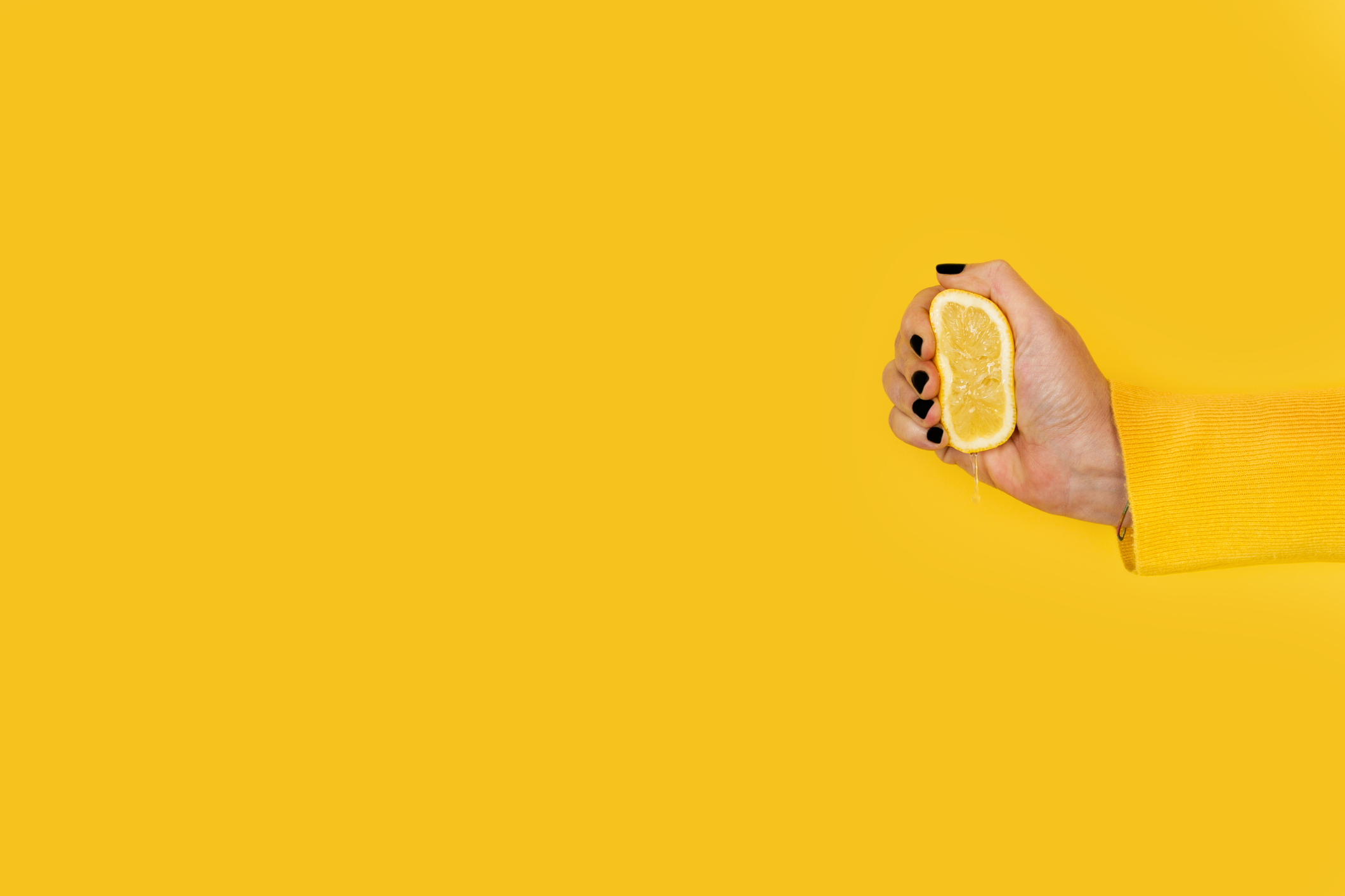 Woman squeezing a half lemon on a yellow background - web based insurance software